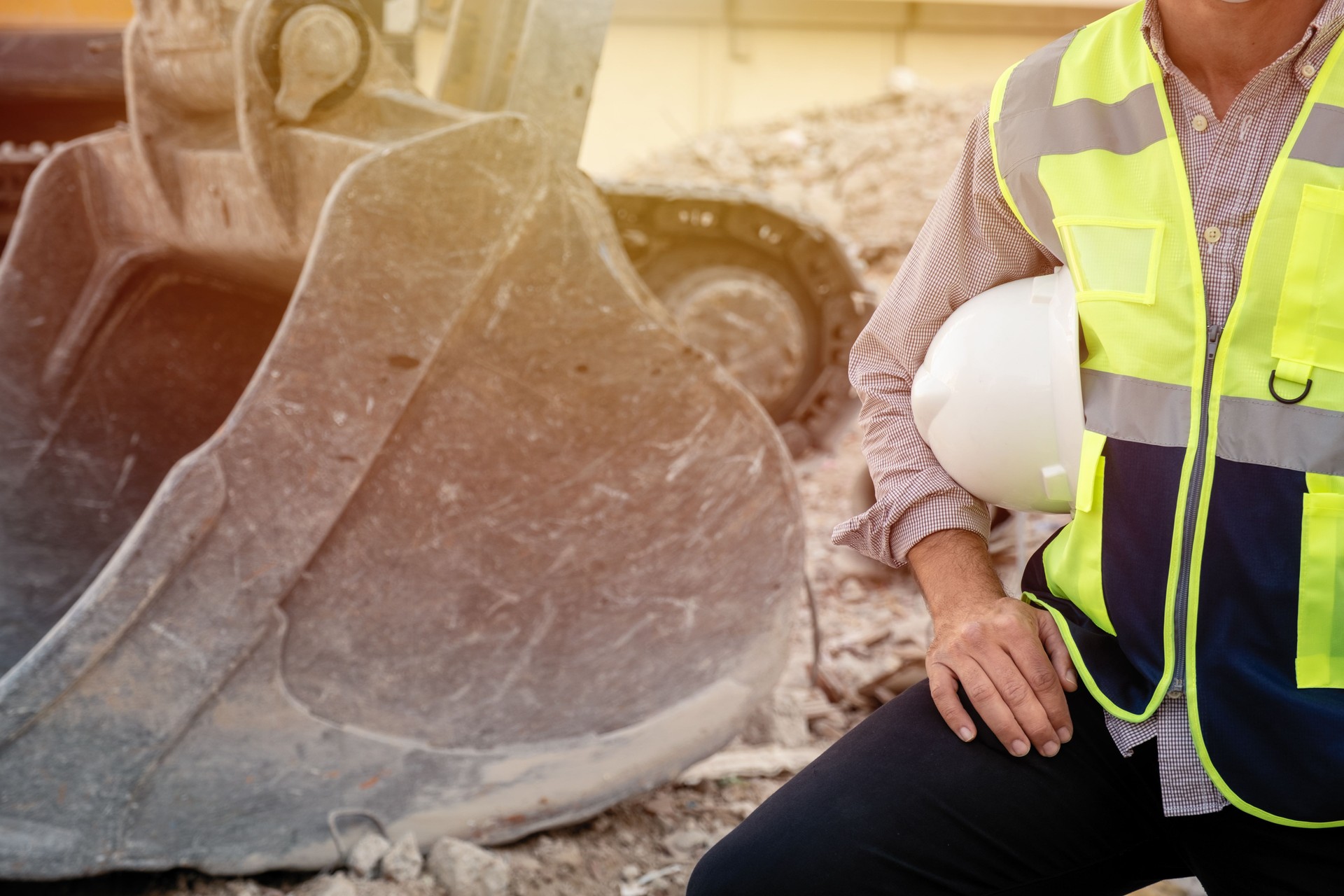 Engineer holding helmet at building  demoliton site with machinery background,safety first concept