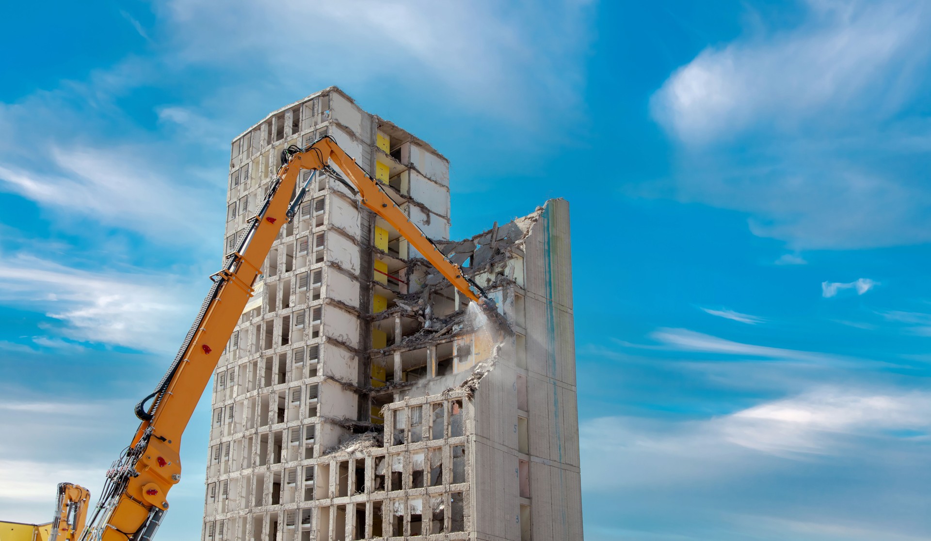 Demolition of the old building. residential house, highrise building at construction site against blue clouds sky.