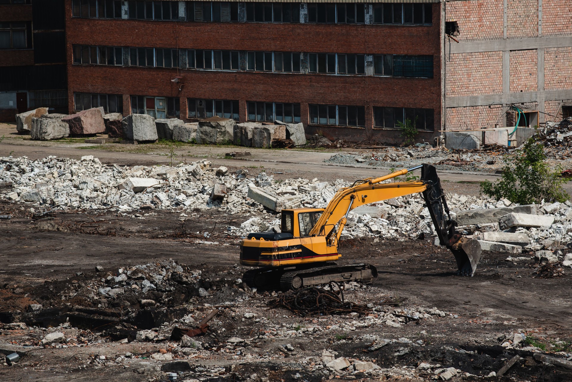 Excavator working on demolition site near abandoned building