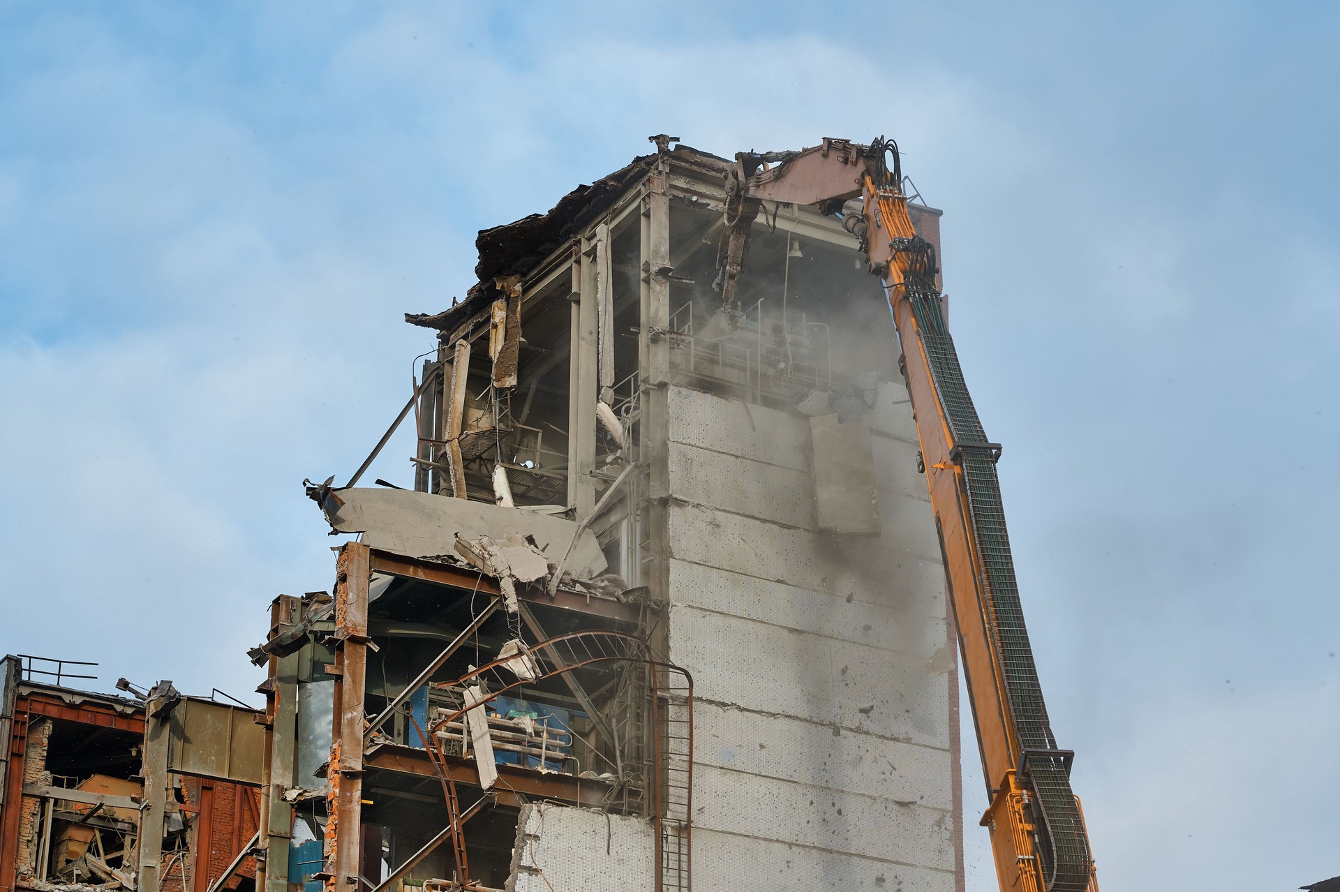 Hydraulic scissors destroy abandoned industrial building